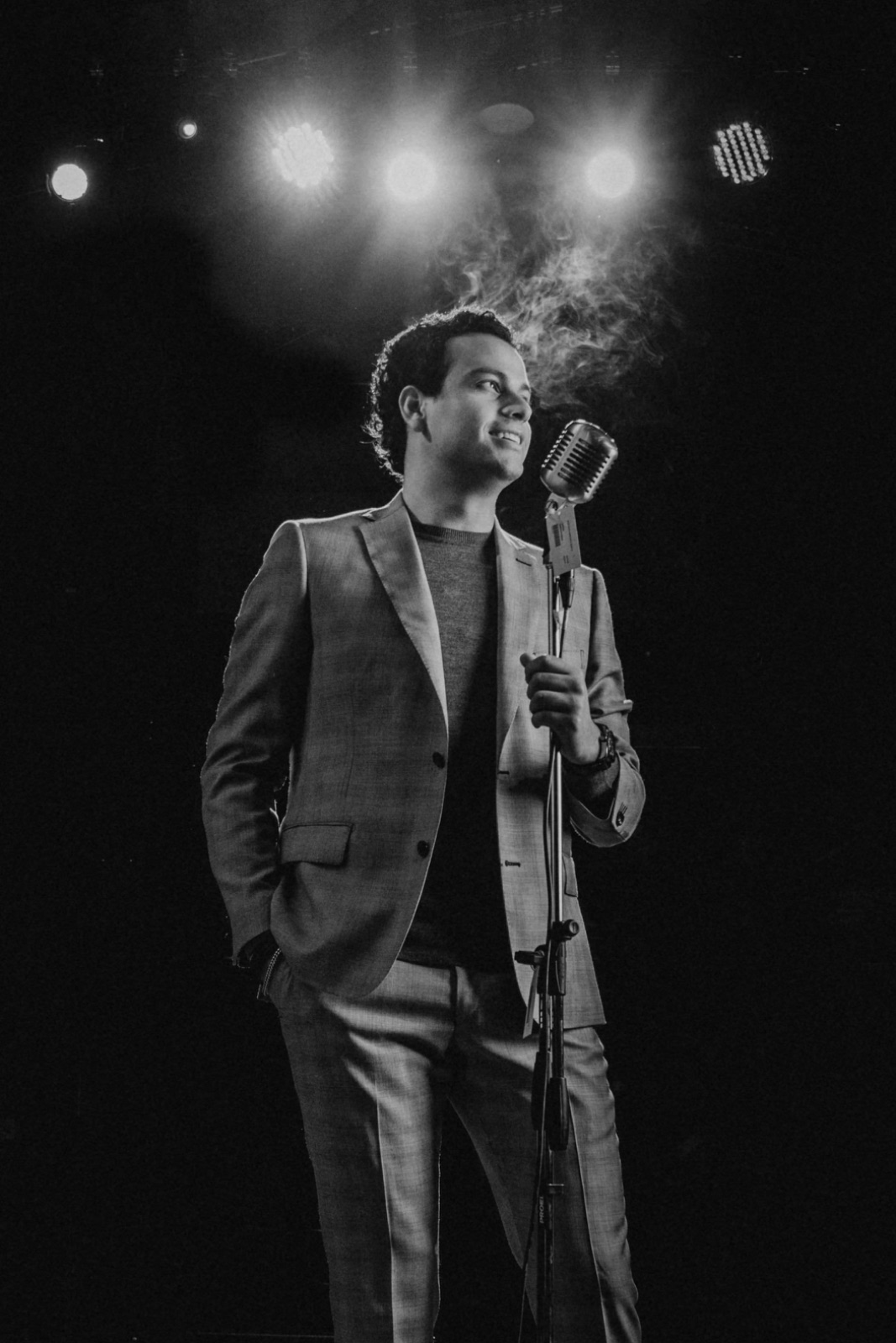 Cantante en escenario con micrófono, iluminación dramática