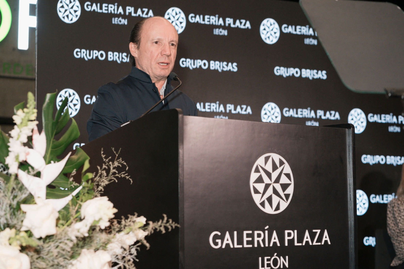 Ponente dando un discurso en un evento corporativo, atril con branding de marca