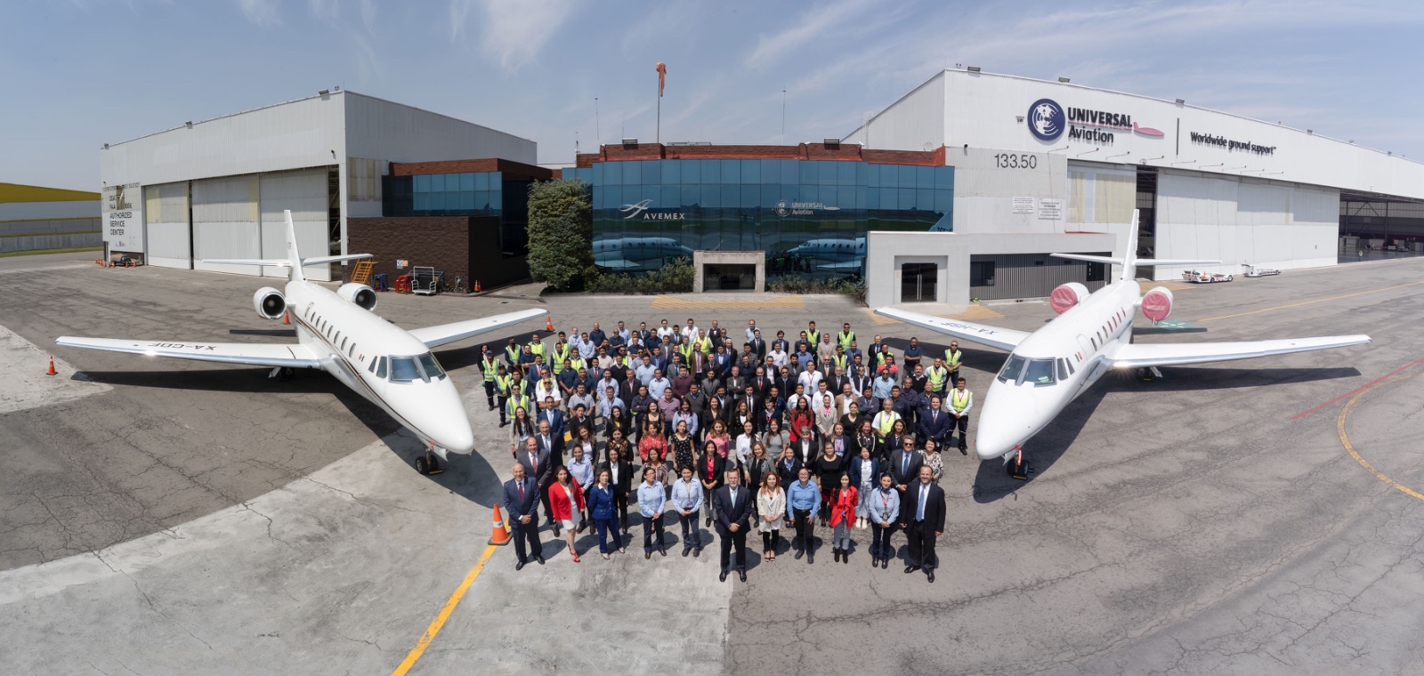 Foto grupal de gran formato frente a una flota de aviones, evento corporativo