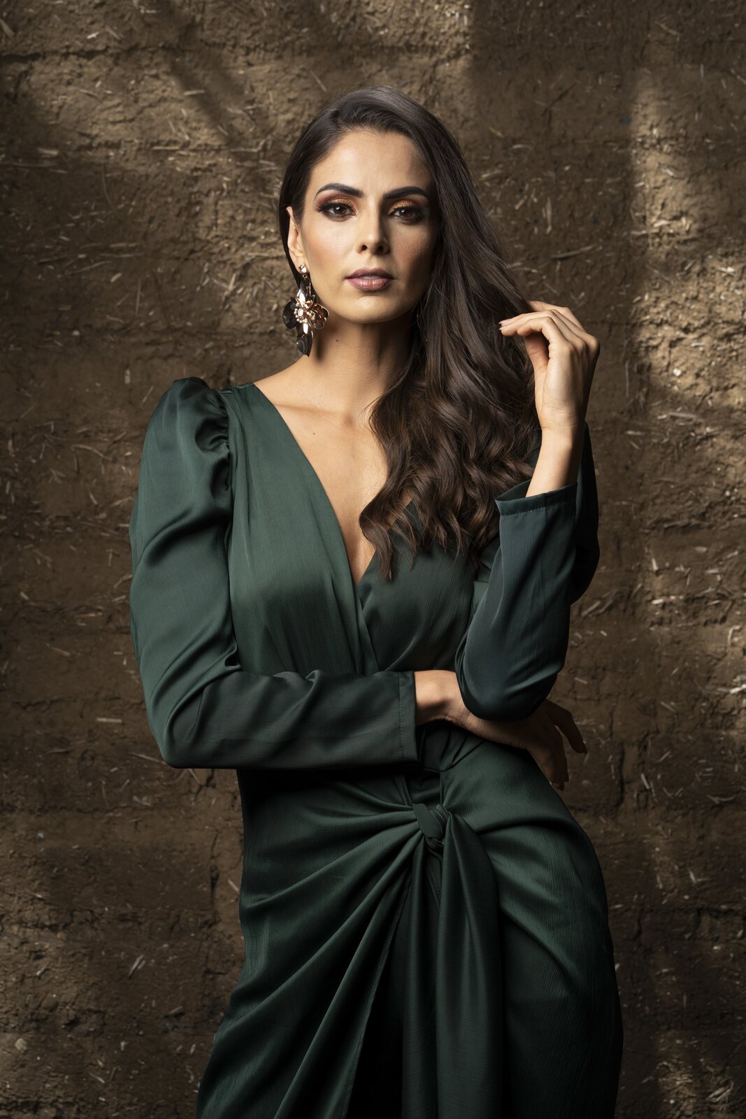 Retrato de una mujer con vestido verde frente a un muro de textura
